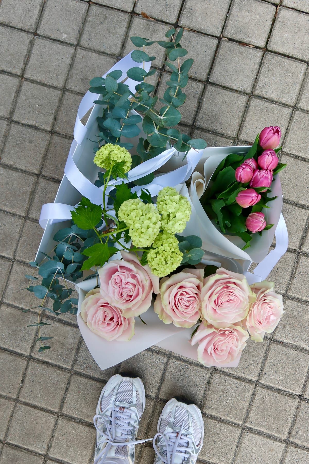 Flat lay of a flower bunch: pink roses, tulips, viburnum and eucalyptus