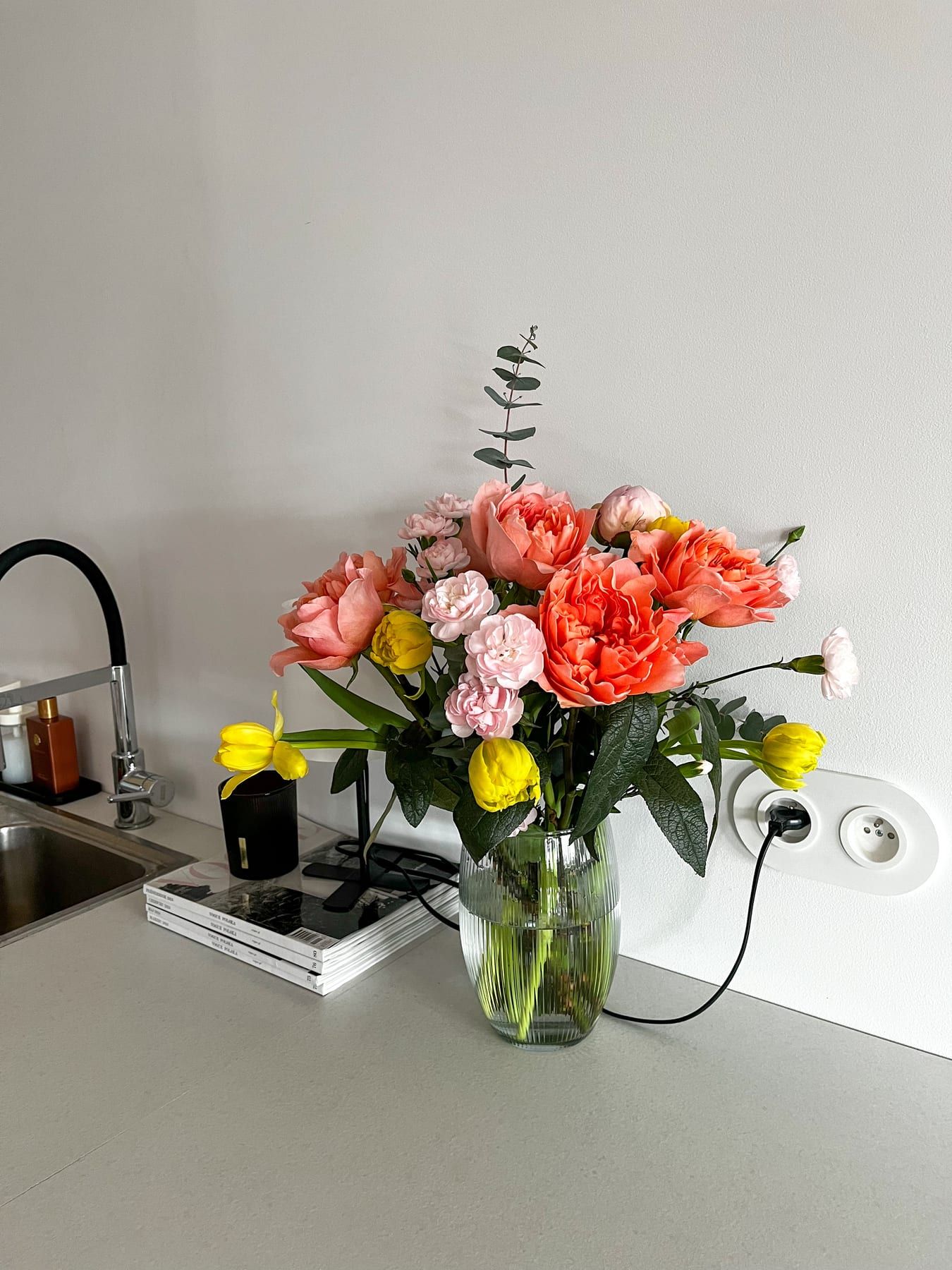 Coral garden roses and yellow tulips in a glass vase